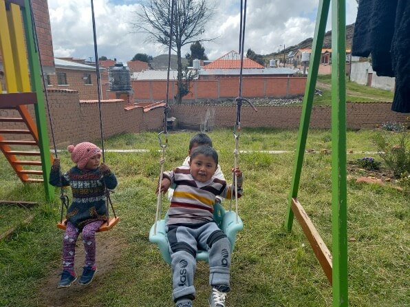 Enfants jouant à la balançoire dans le jardin de la structure d'accueil