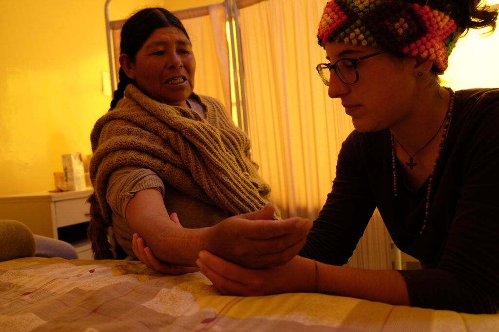 Volontaire faisant un soin kinésithérapeutique à la main d'un femme bolivienne